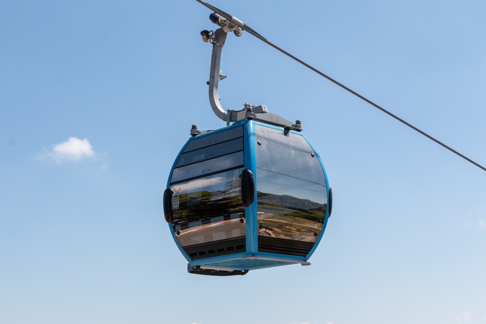 a blue cable car with a sky background
