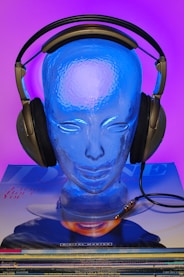 a blue head with headphones on top of a stack of cds