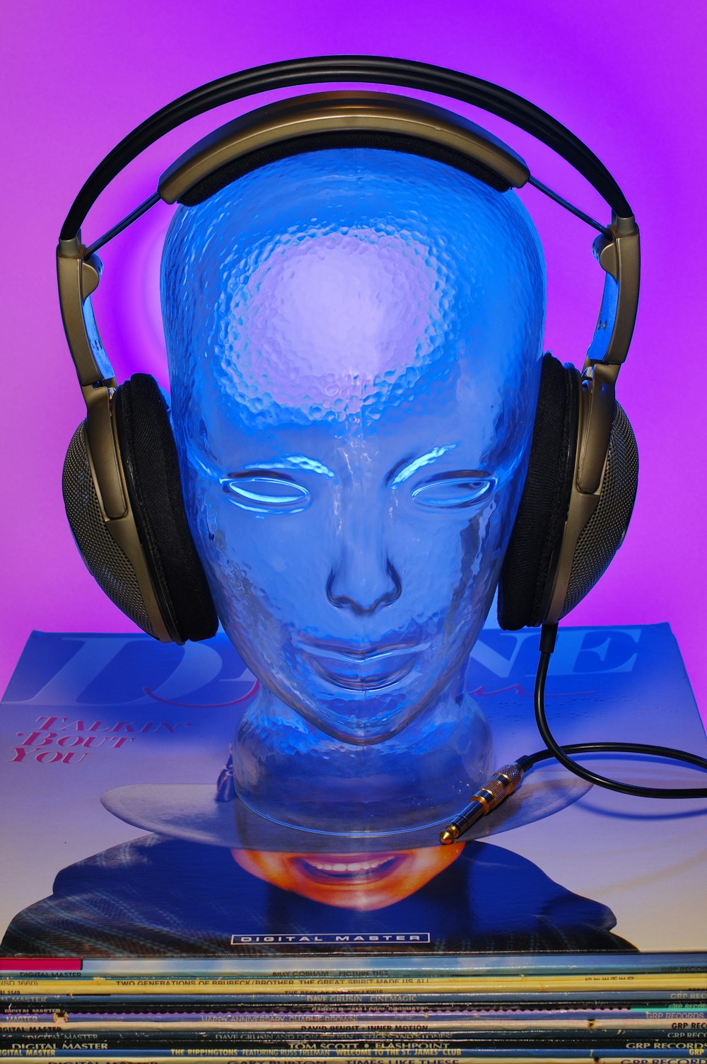 a blue head with headphones on top of a stack of cds