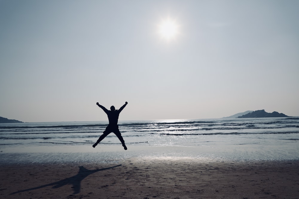 a person jumping in the air on a beach