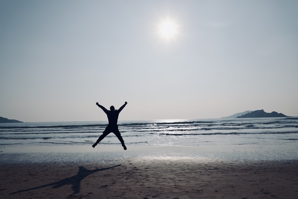 uma pessoa pulando no ar em uma praia