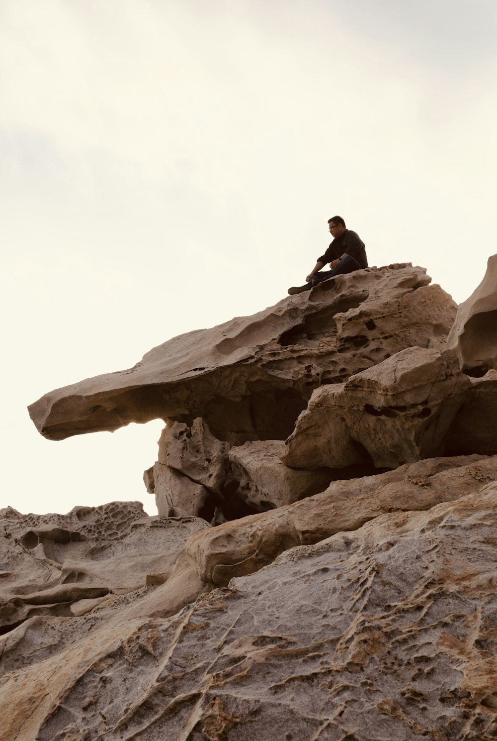 a man sitting on top of a rock formation