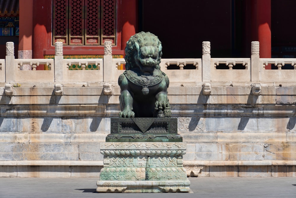 a statue of a lion sitting on a pedestal in front of a building