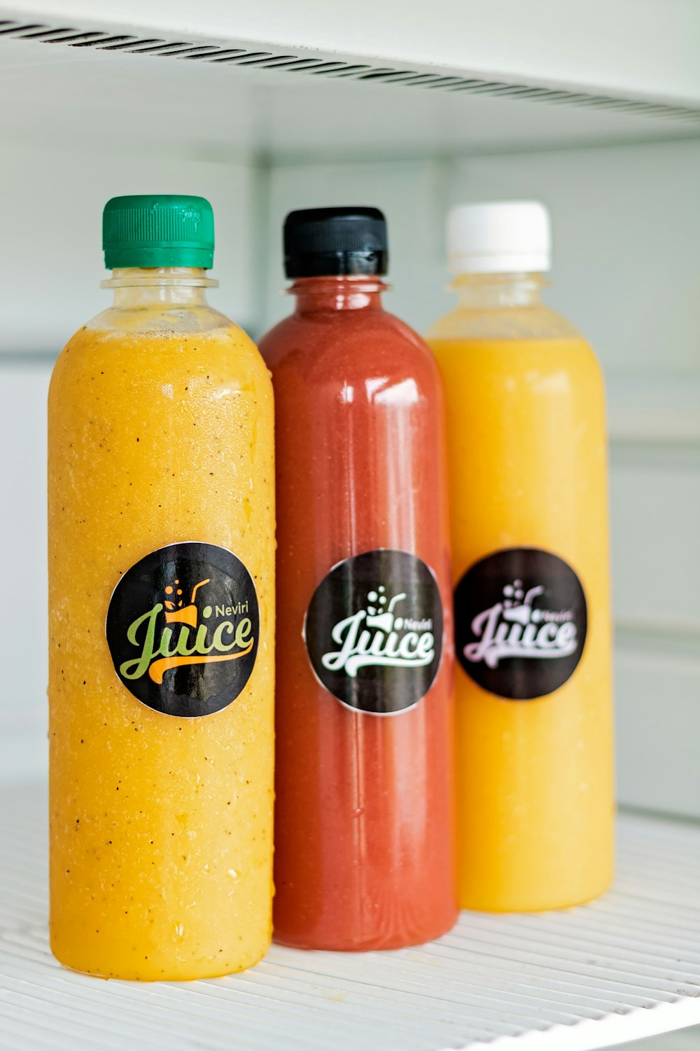 three bottles of juice sitting on a shelf