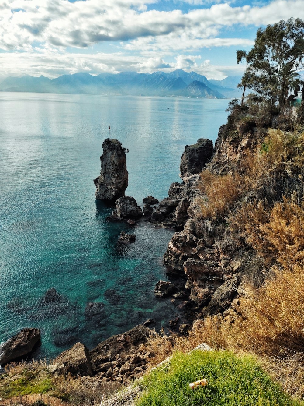 a large body of water sitting next to a lush green hillside