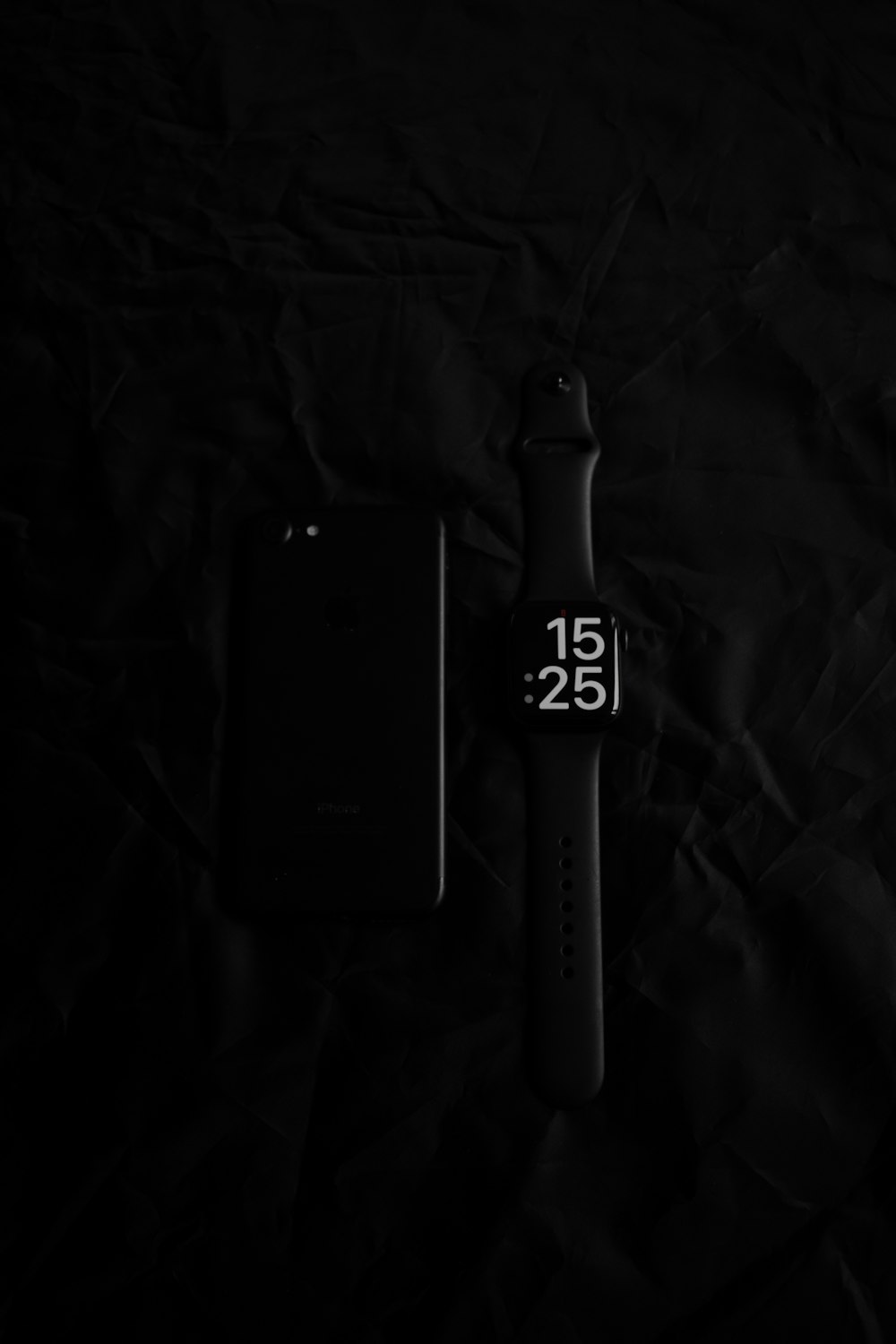 a cell phone and a watch on a black background