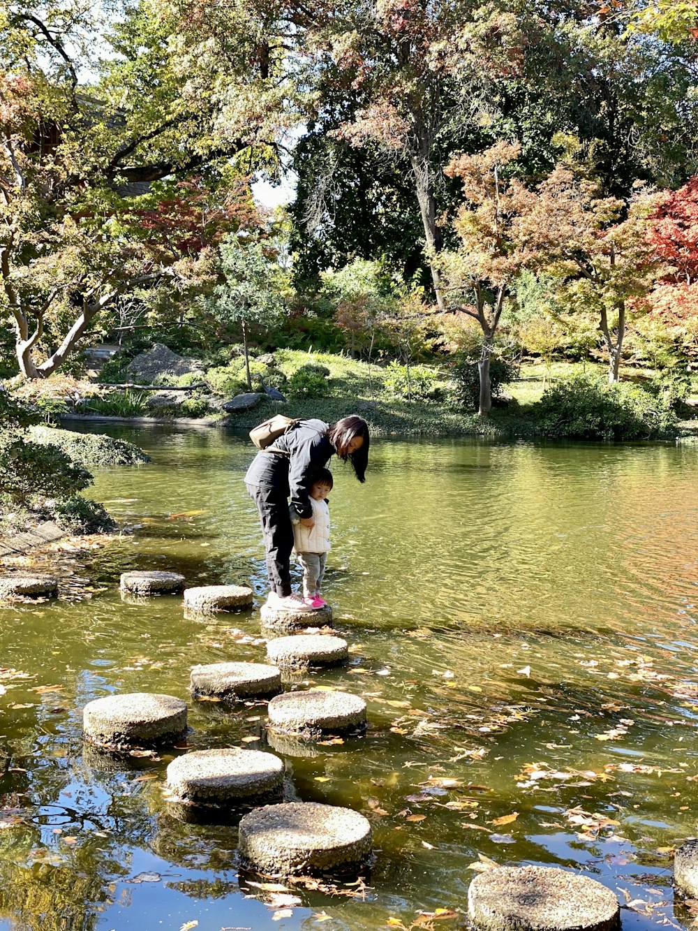 a person standing on stepping stones in a river