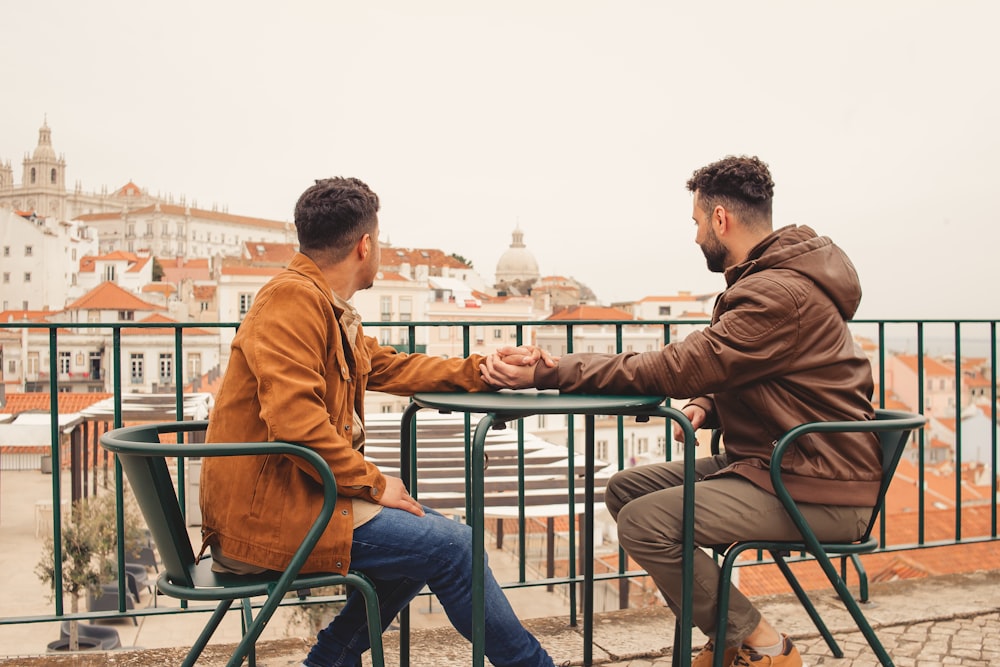 a couple of men sitting at a table next to each other