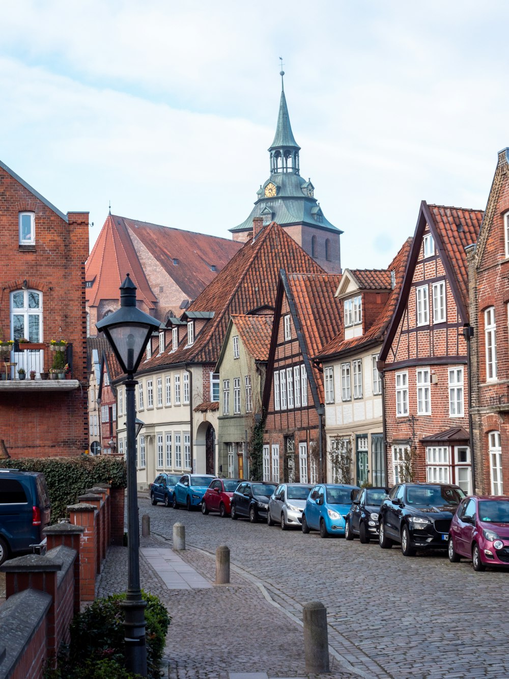 a row of parked cars on a cobblestone street