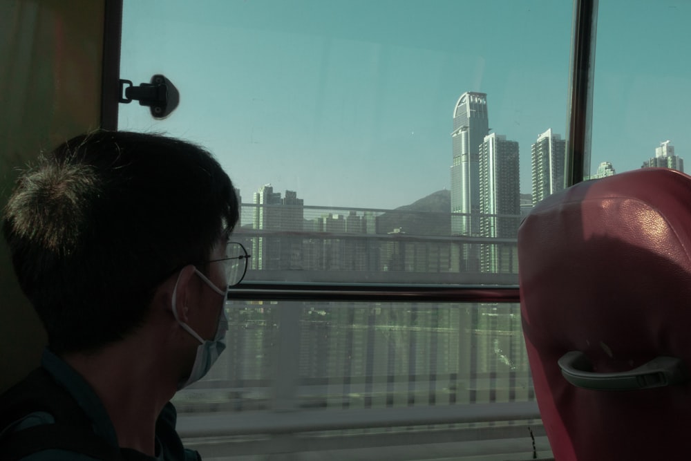 a man wearing a face mask looking out a window