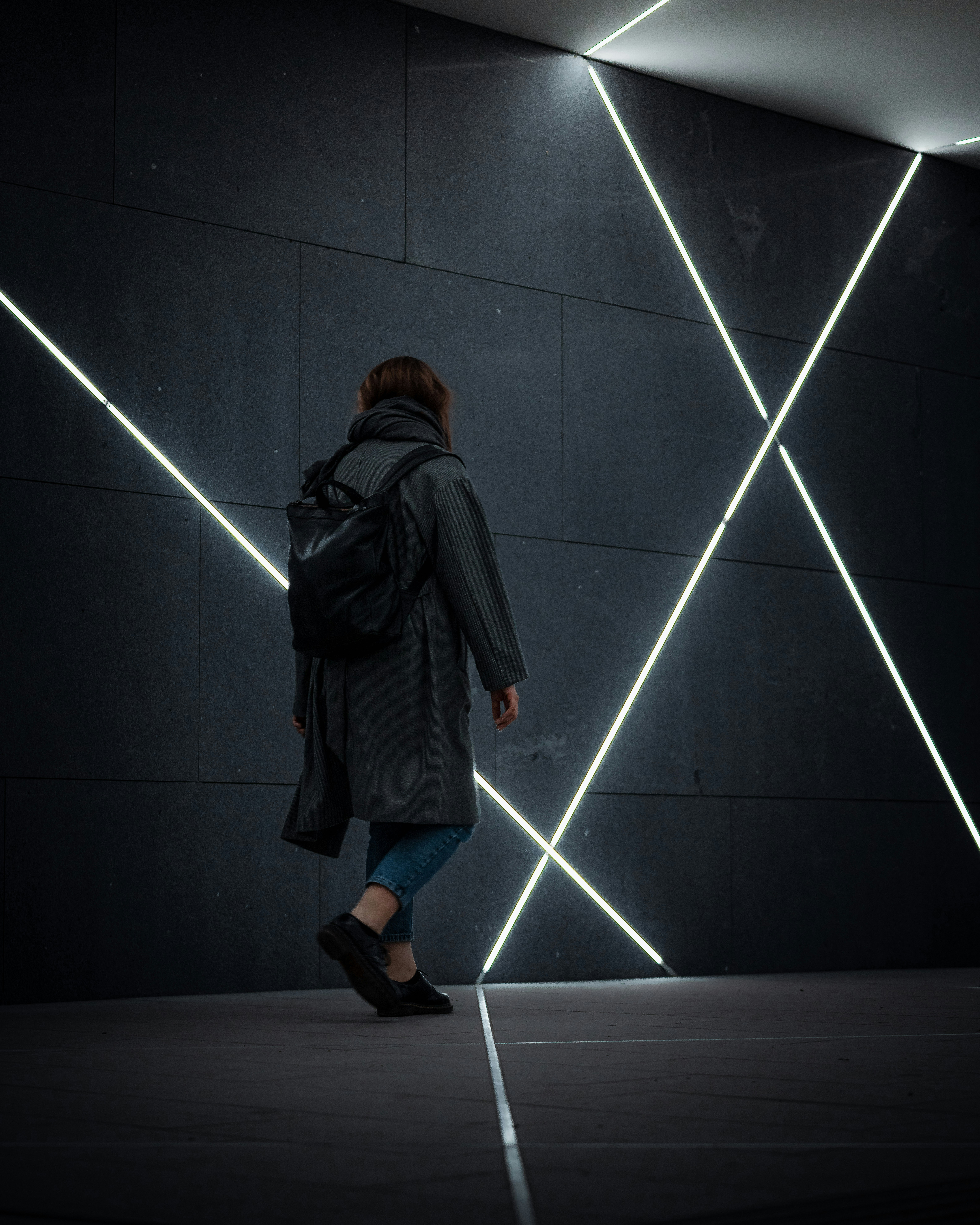 a woman with a backpack walking in a dark room