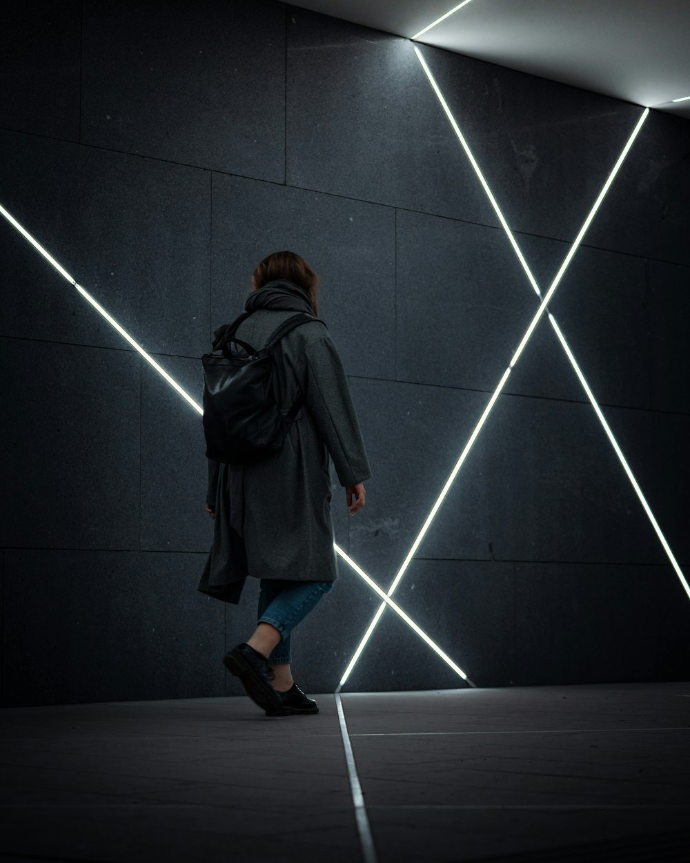 a woman with a backpack walking in a dark room