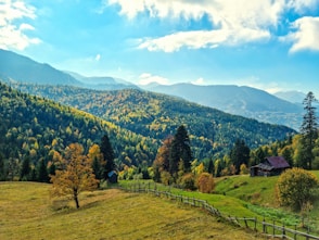 a scenic view of a mountain range with a cabin in the foreground