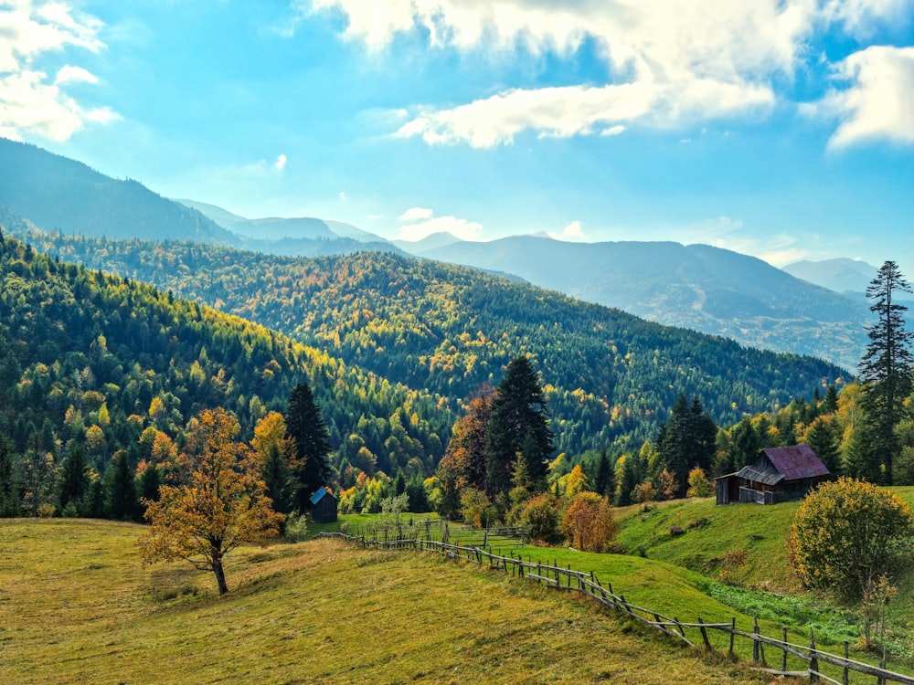 a scenic view of a mountain range with a cabin in the foreground