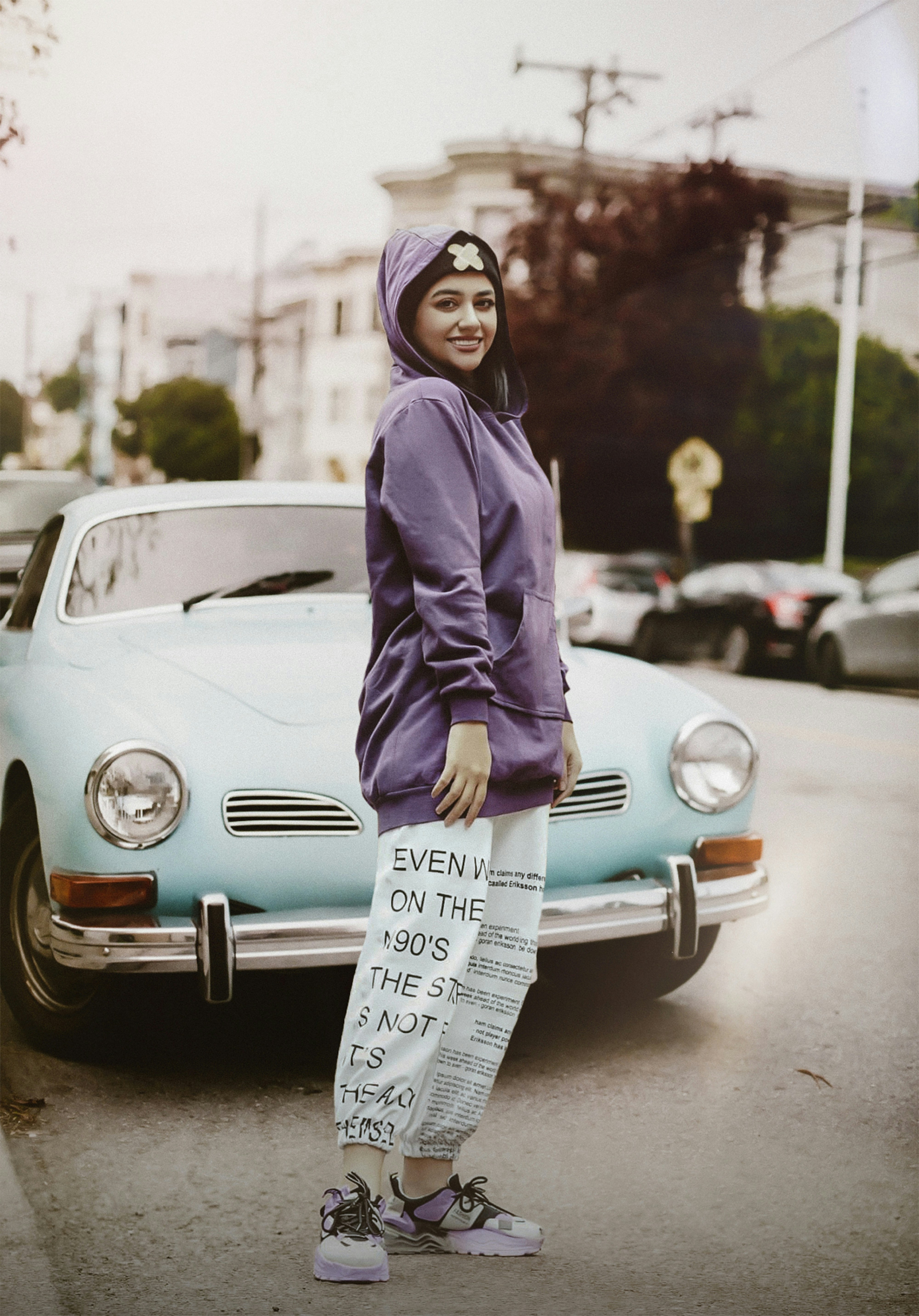 a woman standing in front of a blue car