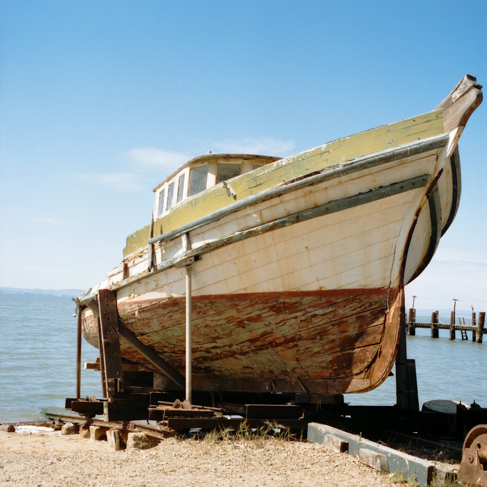 a boat sitting on top of a beach next to a body of water