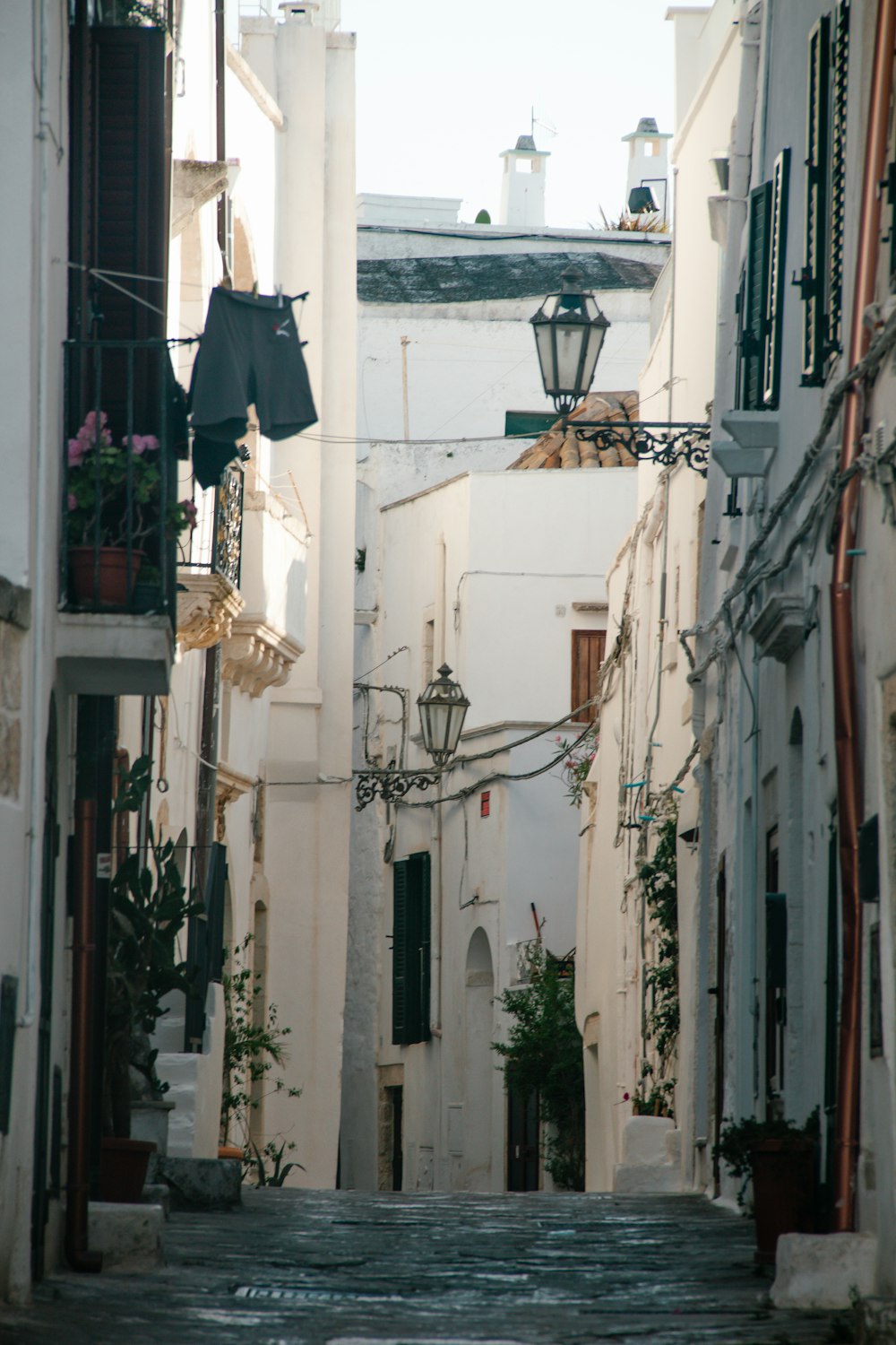 a narrow alleyway with white buildings and a street lamp
