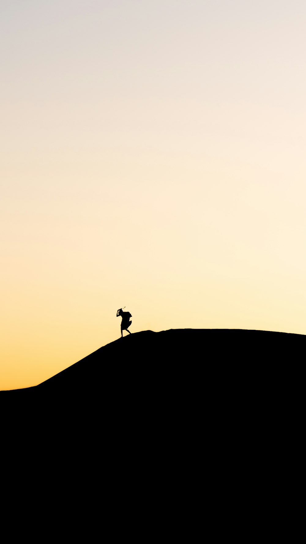 una silhouette di una persona in piedi sulla cima di una collina
