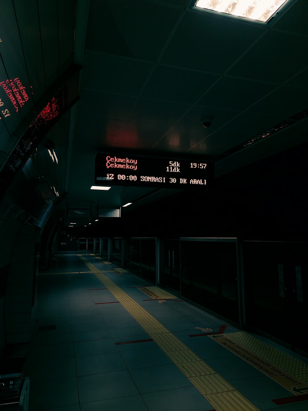a dimly lit subway station with red and white signs