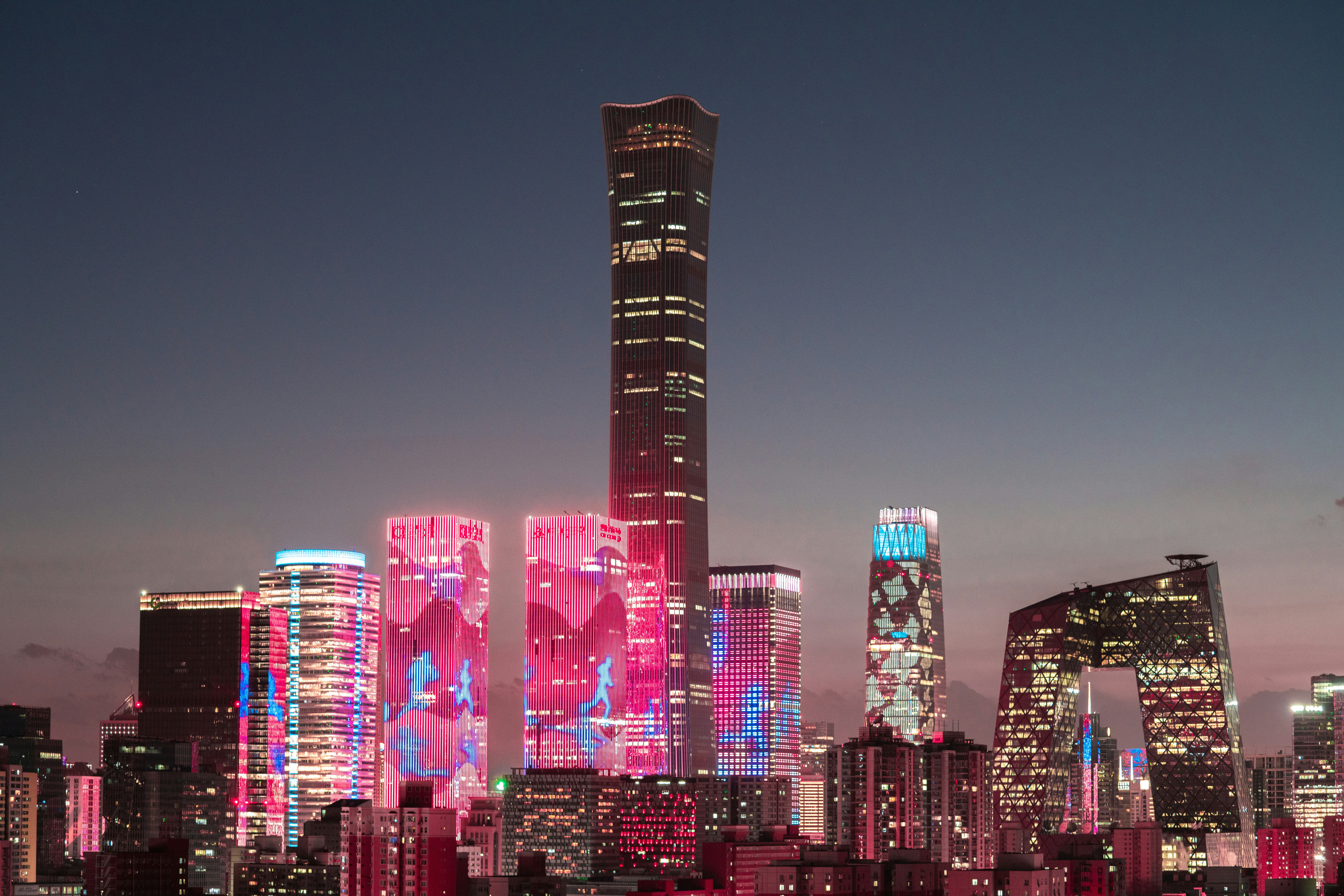 A city skyline with a lot of tall buildings lit up at night photo ...