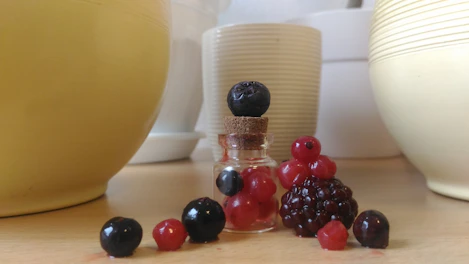 Assortment of dried berries in small glass jars on a minimalist white surface