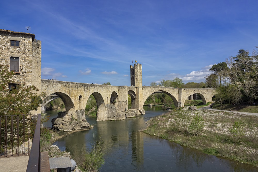 a stone bridge over a river next to a tall building