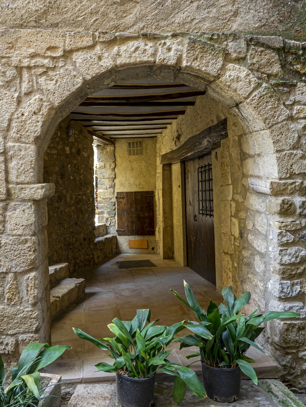 a stone building with two potted plants in front of it