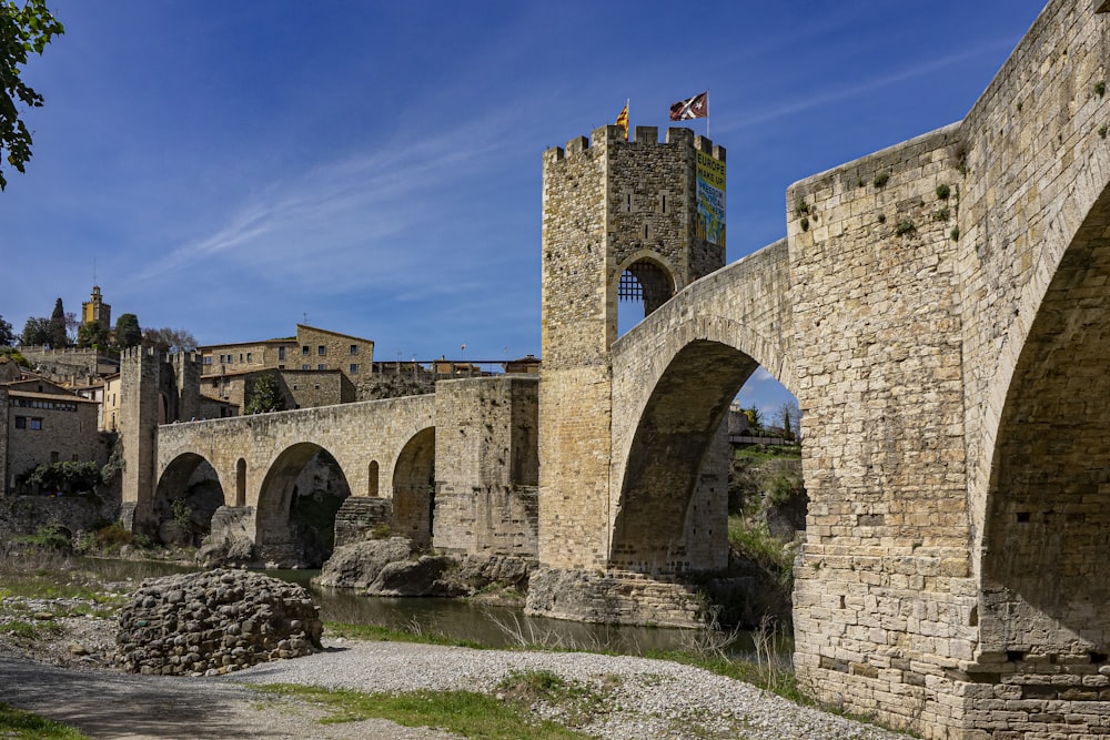 a stone bridge over a river next to a tall building