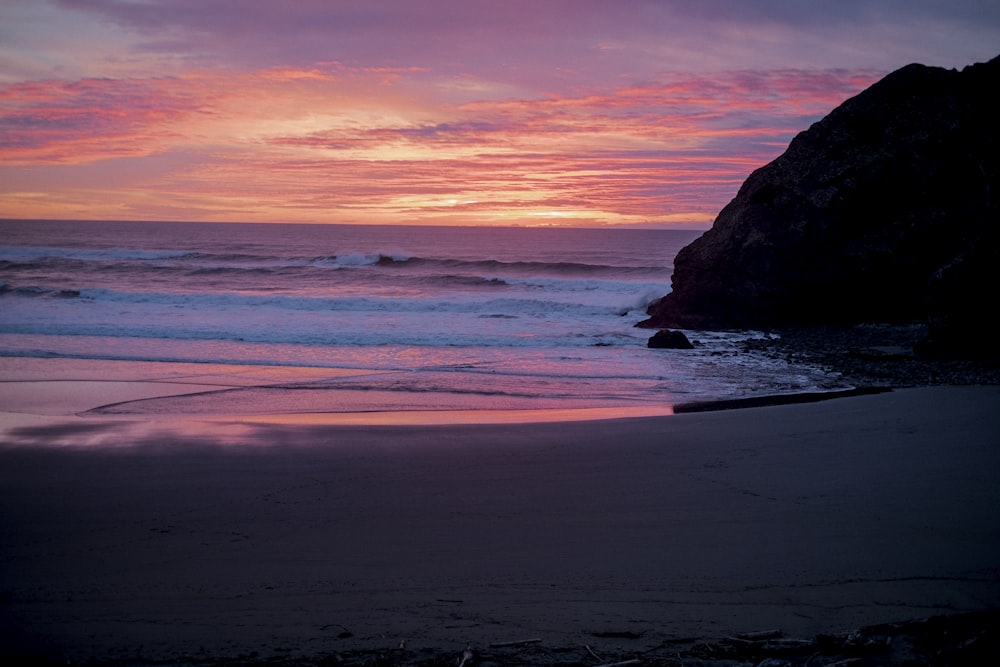 a sunset view of a beach with waves coming in