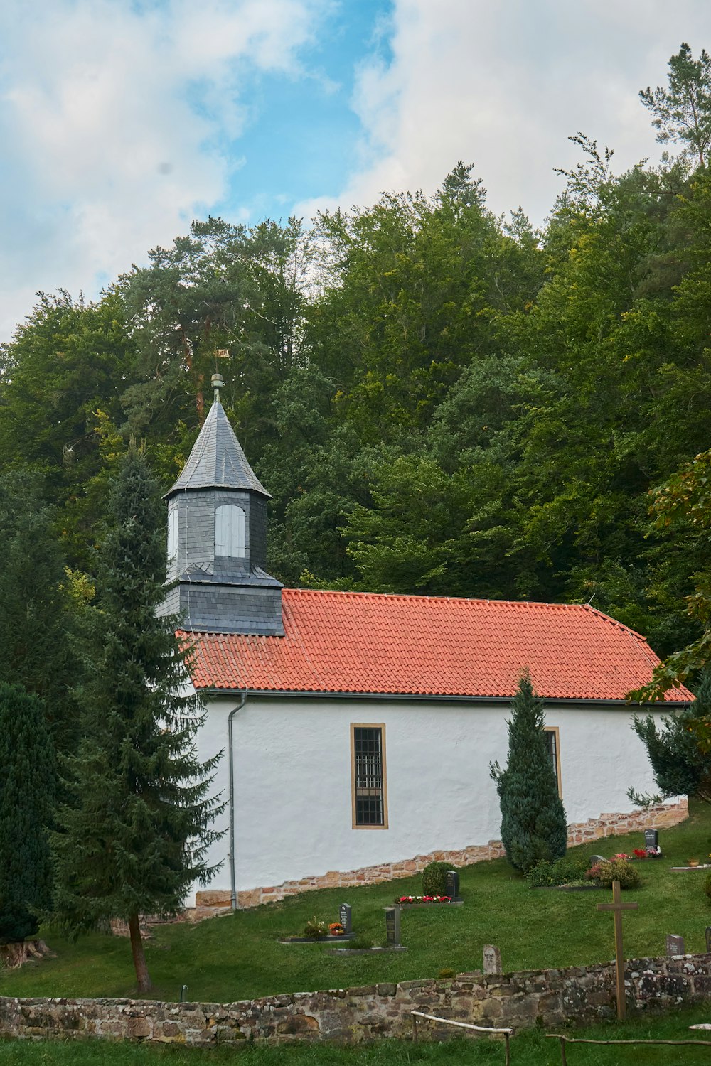 a white church with a red roof surrounded by trees