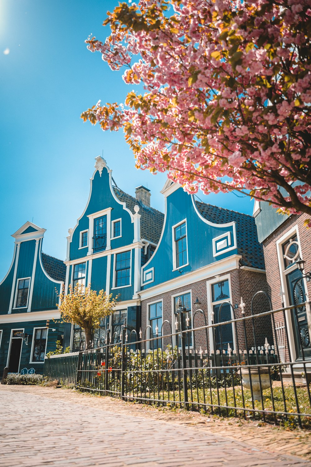 a large blue house with a fence and trees in front of it