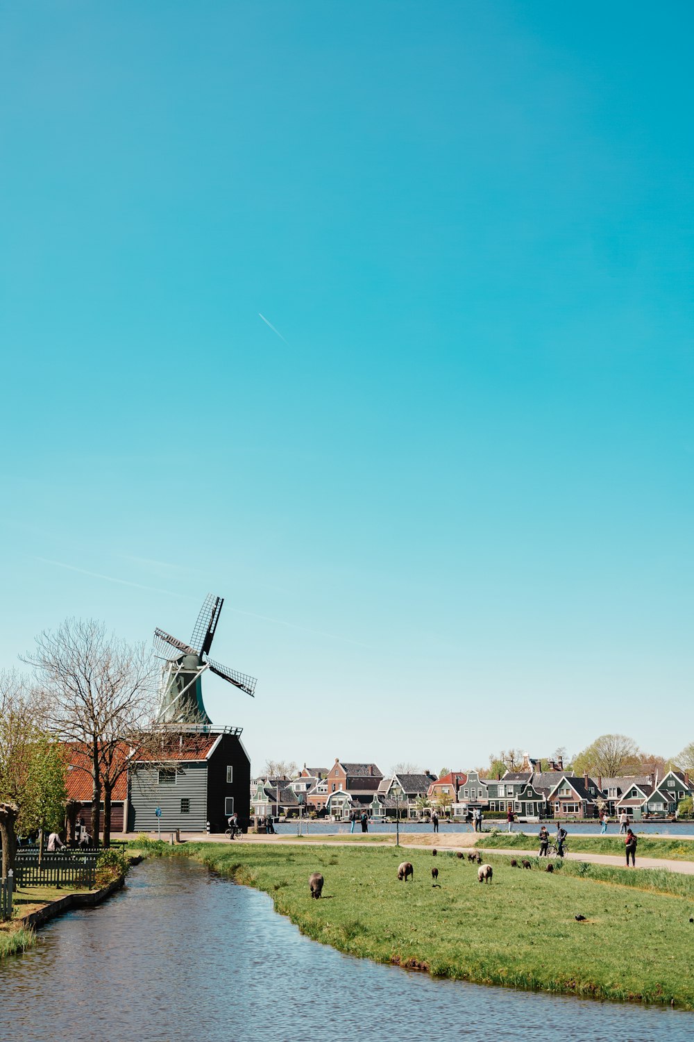 a windmill in the middle of a field next to a river