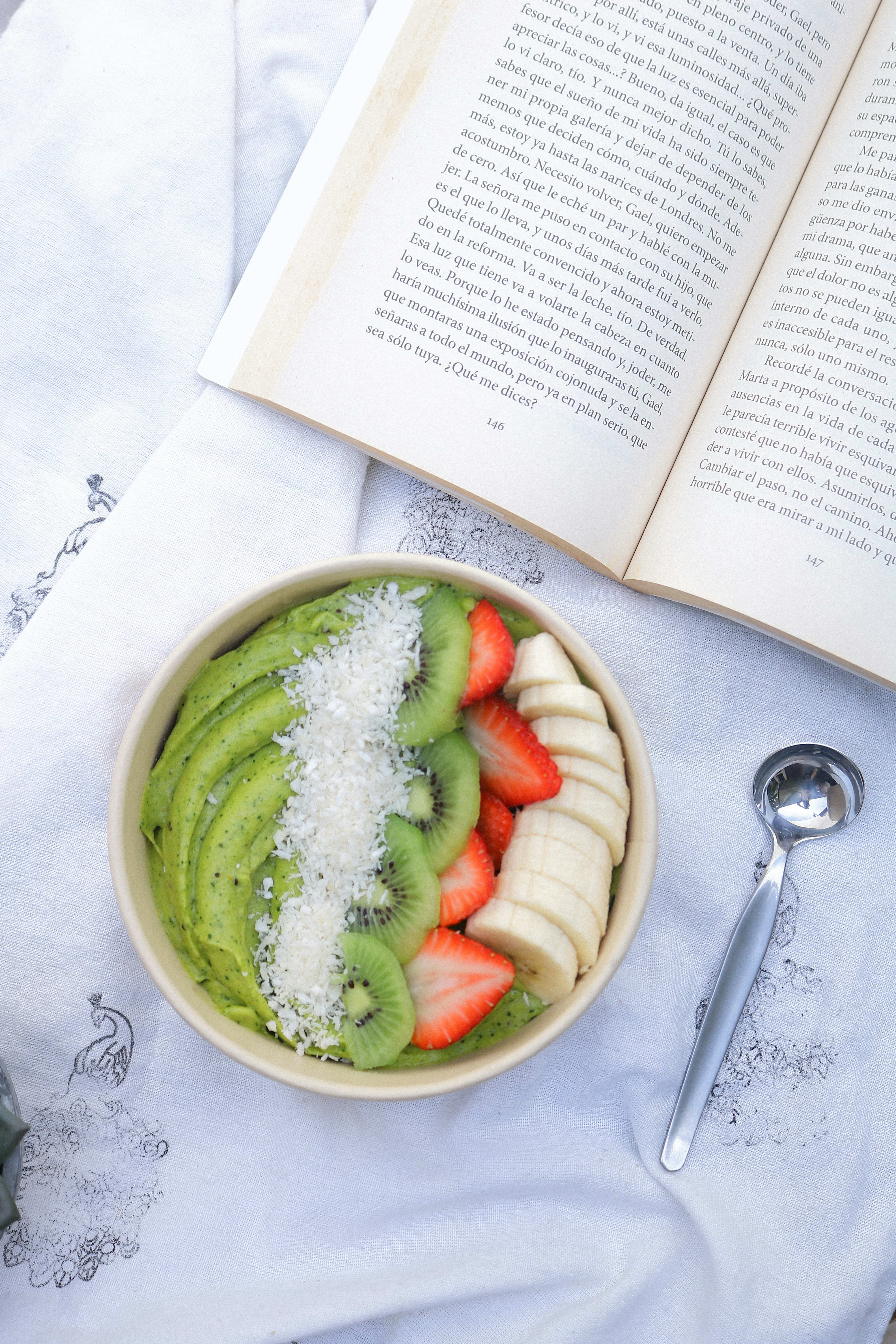 a bowl of fruit and a book on a table