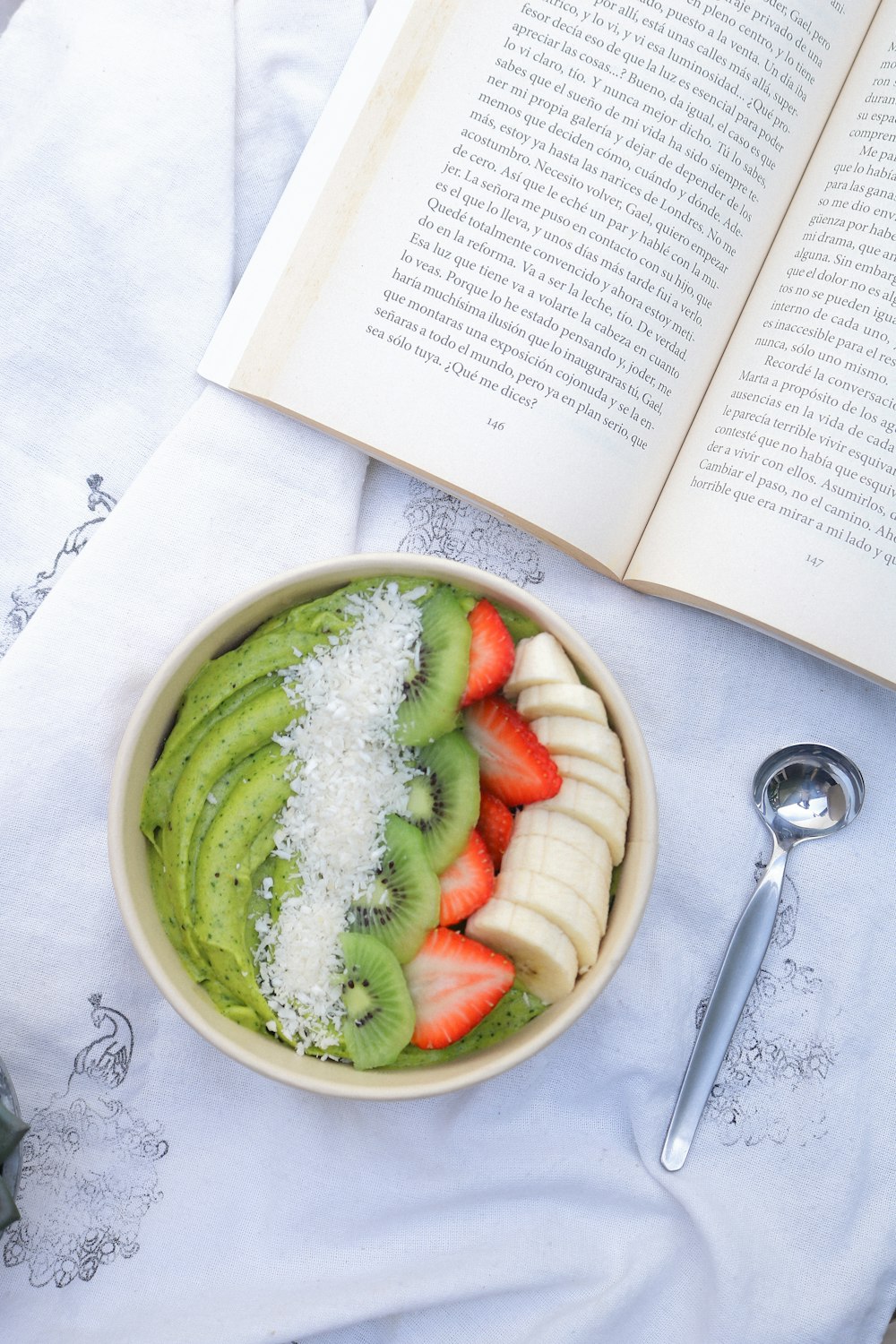 a bowl of fruit and a book on a table