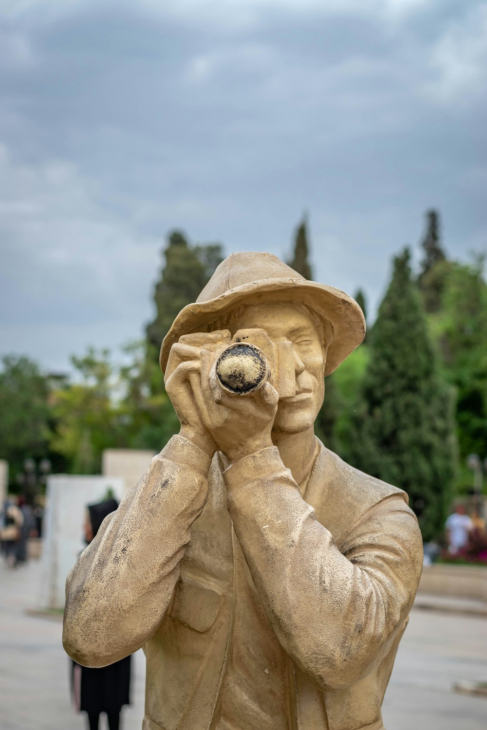 a statue of a man wearing a hat and holding his hands to his face