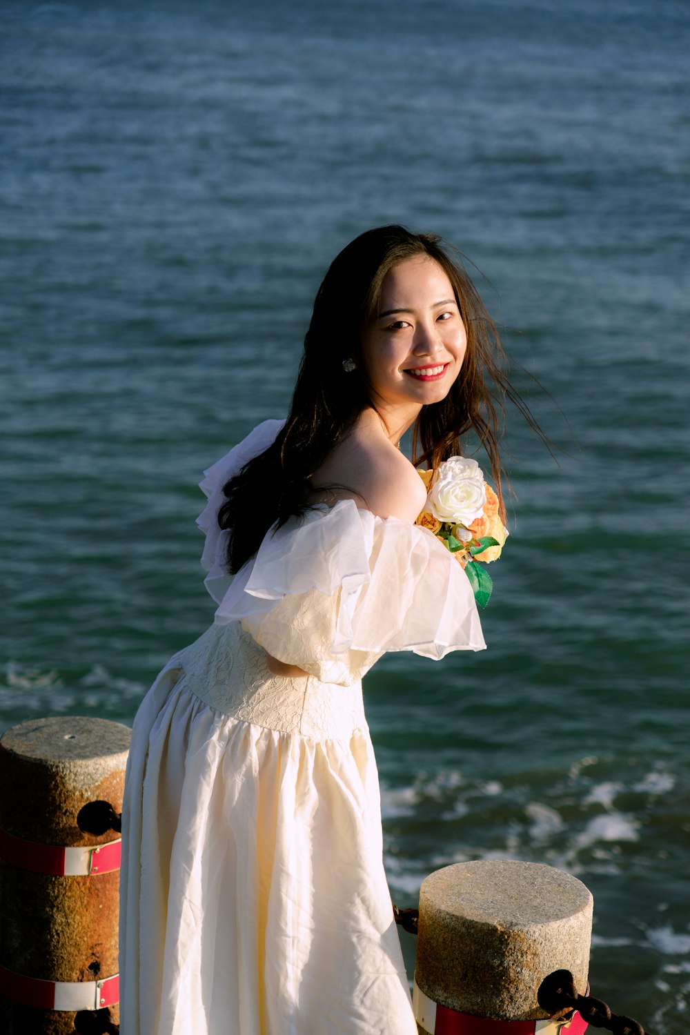 a woman in a white dress standing next to a body of water