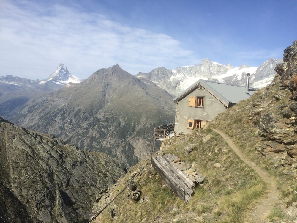 a house on the side of a mountain with mountains in the background