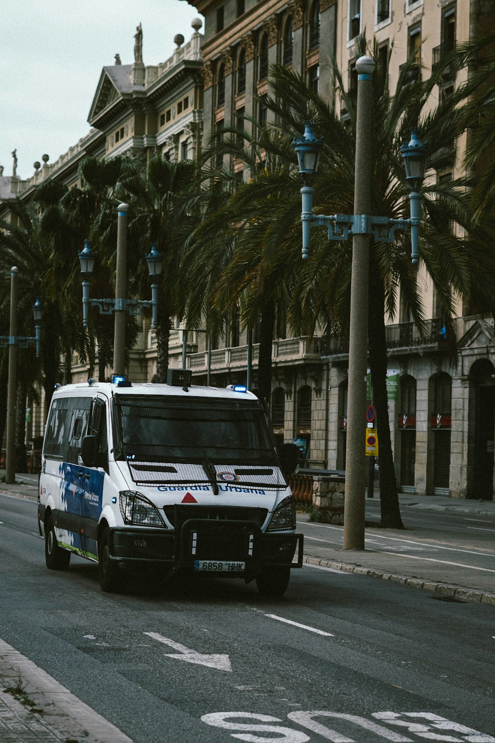 a police van driving down a street next to palm trees