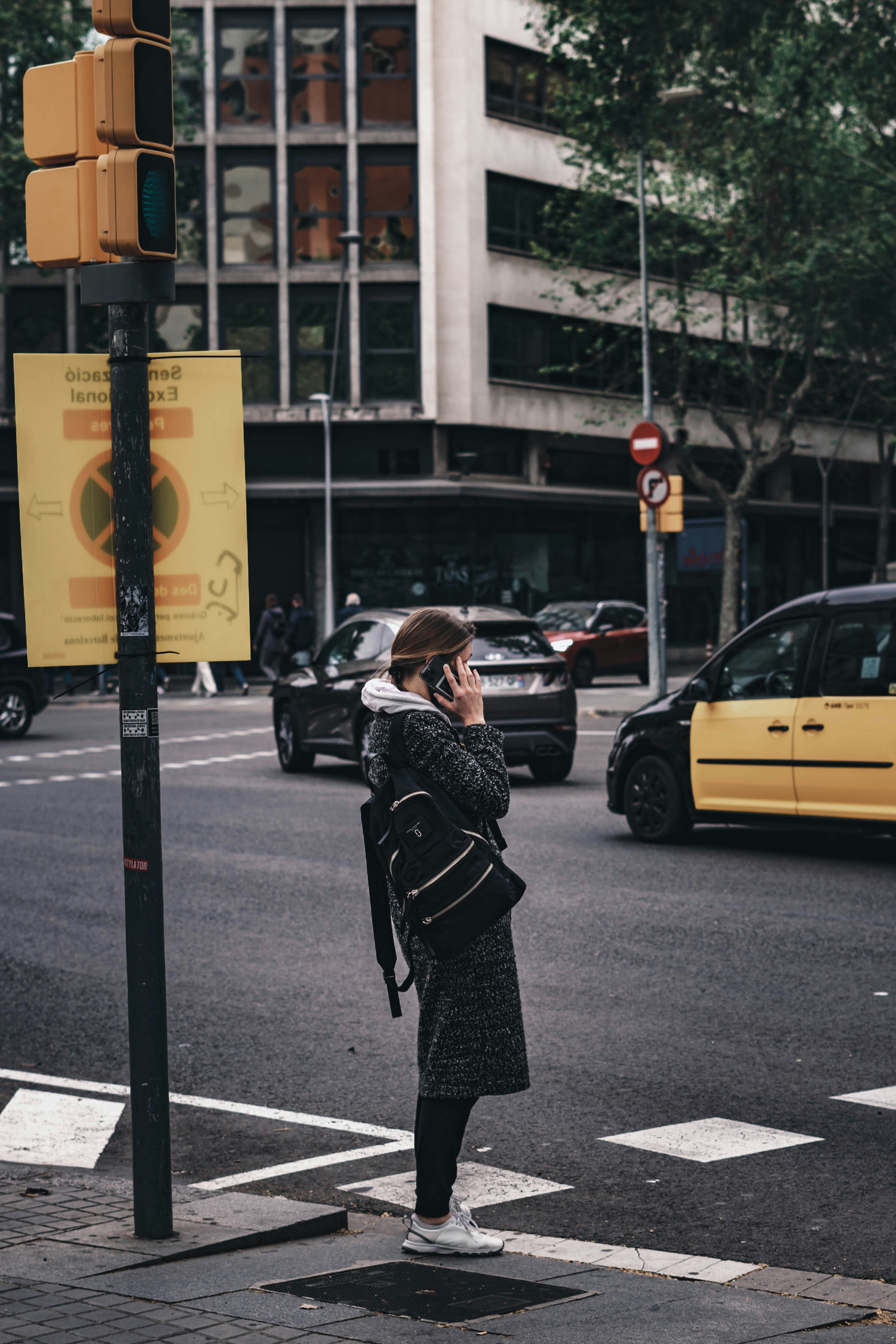 a woman standing on the side of a street talking on a cell phone