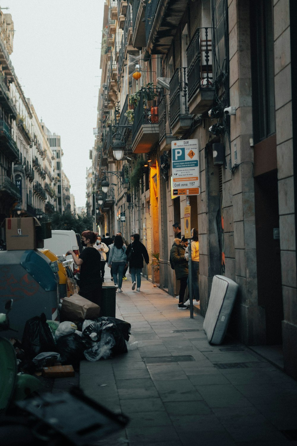 a group of people walking down a street next to tall buildings