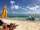 Smiling woman enjoying a sunny beach vacation with bright yellow umbrella