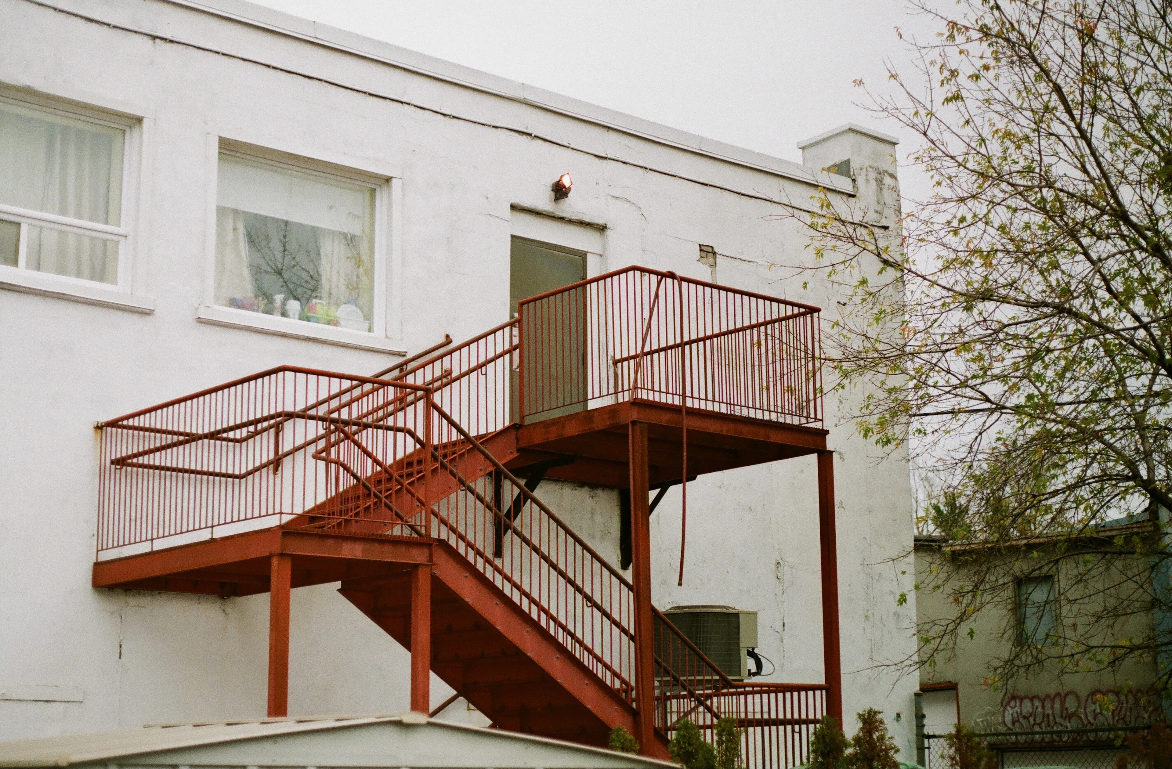 Un escalier extérieur rouge mène à l’étage d’une maison de Montréal, typique des plex de la ville