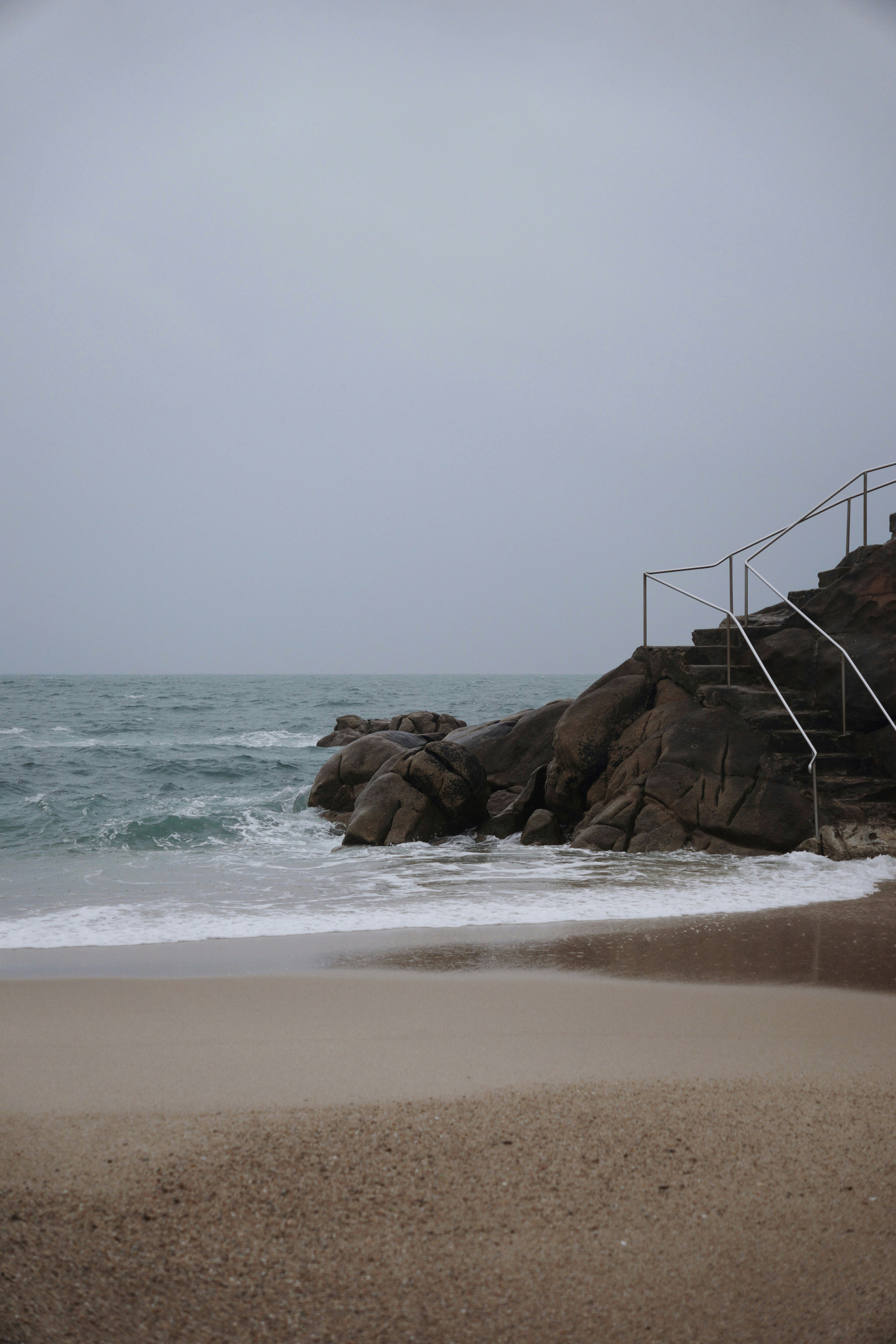 une plage avec des rochers et une clôture
