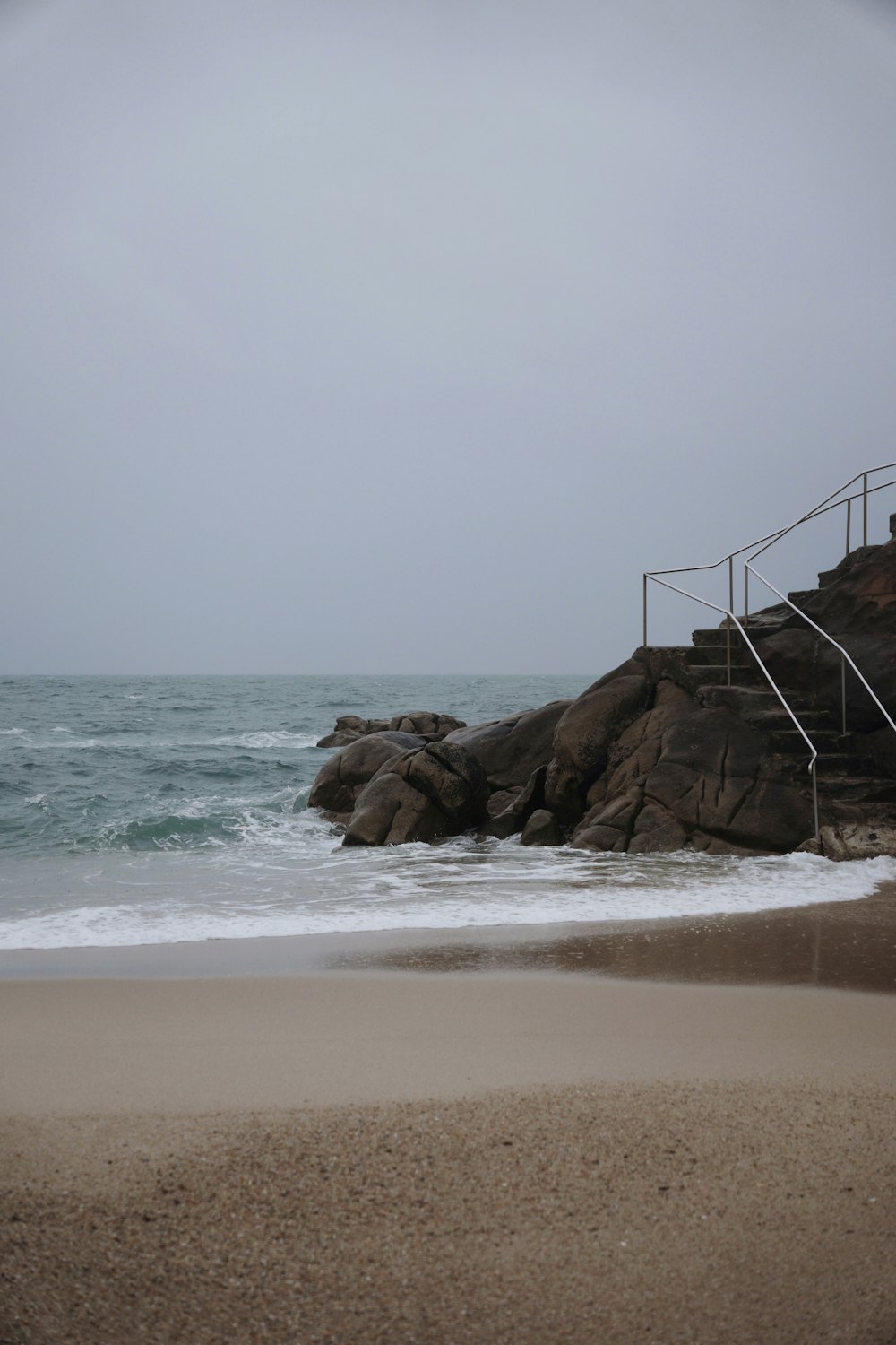 a beach with rocks and a fence