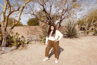 A cheerful young Brazilian woman with indigenous features standing in front of a desert landscape with a pile of clothes.