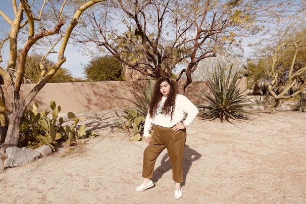 A cheerful young Brazilian woman with indigenous features standing in front of a desert landscape with a pile of clothes.