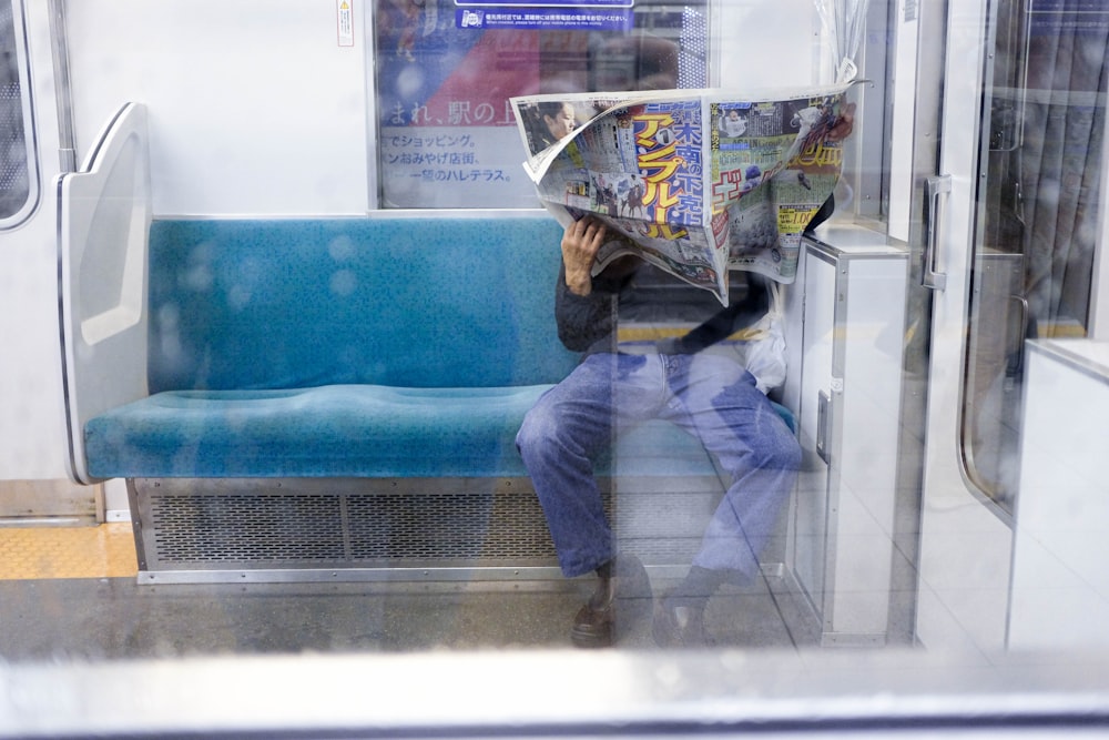 a man reading a newspaper on a subway