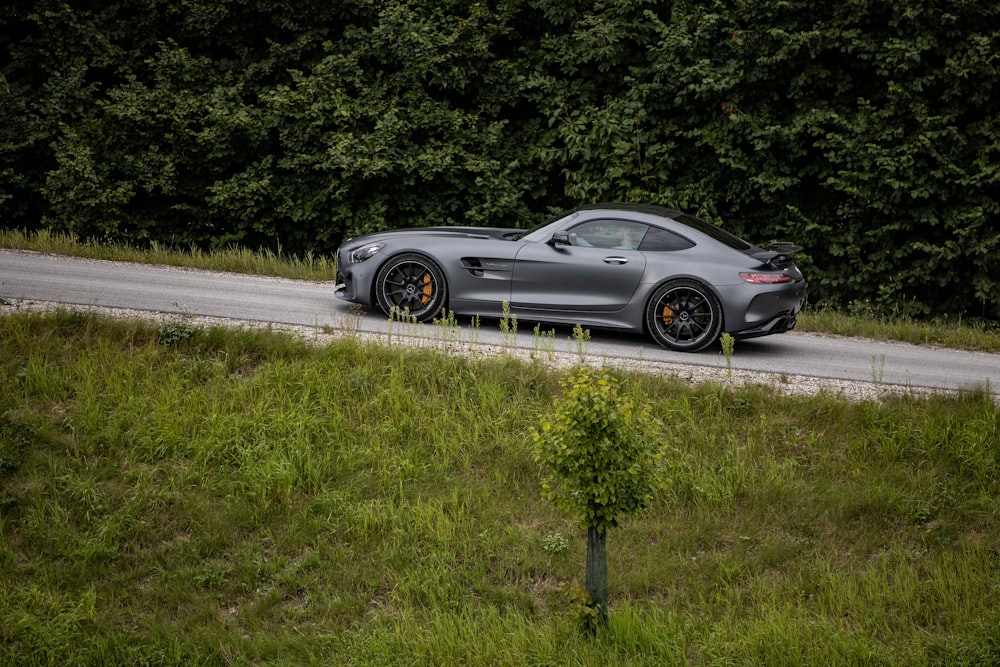 a silver sports car parked on a road with trees in the background