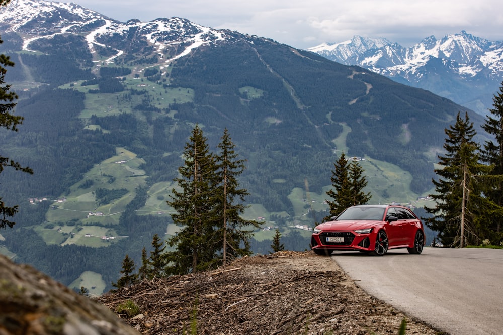 a red sports car on a road with mountains in the background