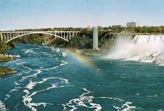 a large waterfall with a bridge in the background